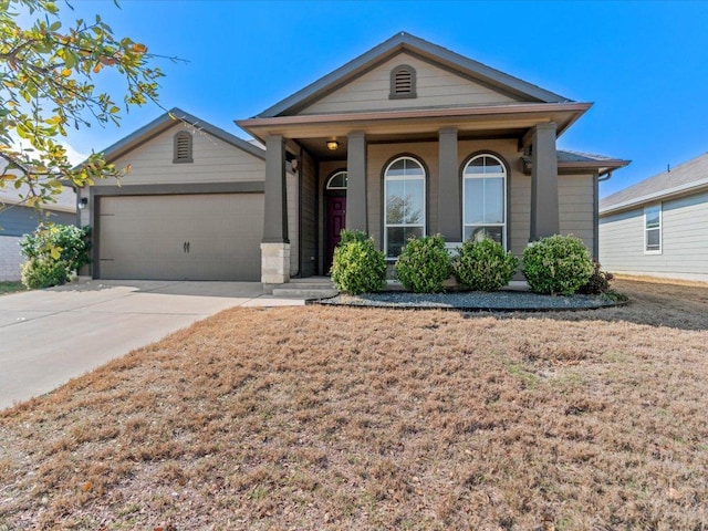 single story home featuring a front yard, driveway, an attached garage, and covered porch