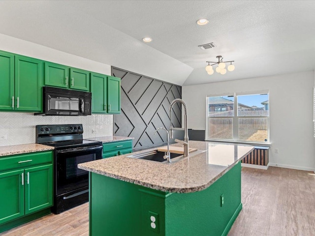 kitchen with visible vents, a sink, black appliances, light wood-style floors, and backsplash