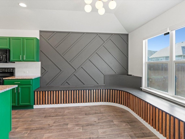 interior space featuring light wood-type flooring, black appliances, light countertops, green cabinetry, and decorative backsplash