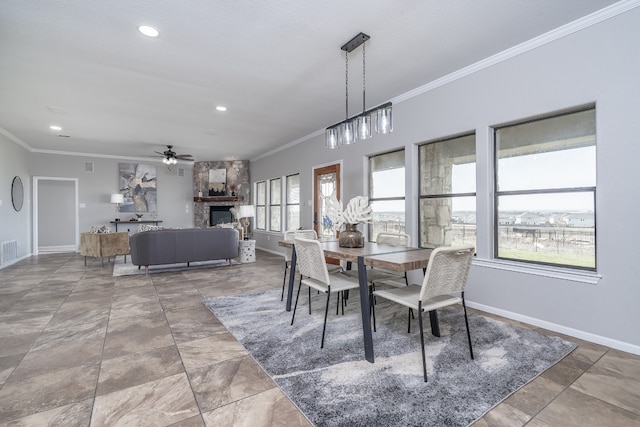 dining space featuring a stone fireplace, baseboards, crown molding, and visible vents