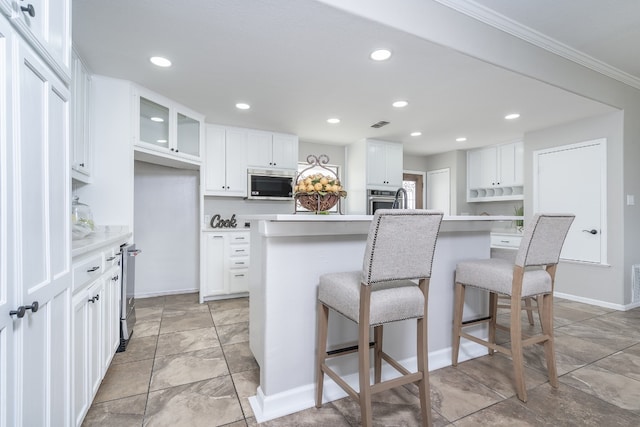 kitchen with stainless steel appliances, a kitchen breakfast bar, an island with sink, and white cabinets