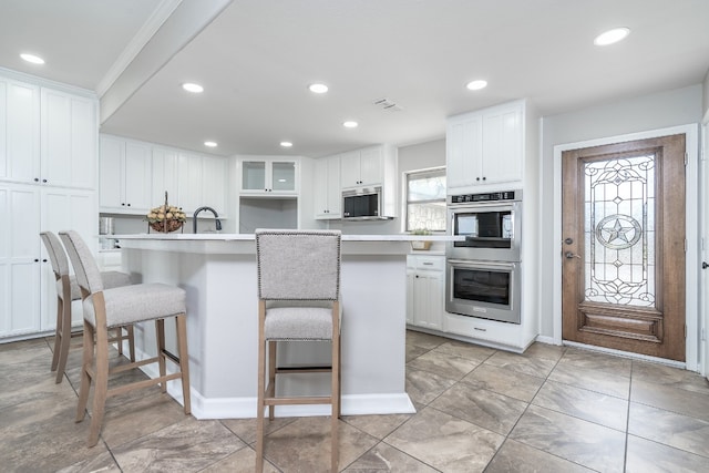 kitchen with a breakfast bar, recessed lighting, stainless steel appliances, white cabinets, and light countertops