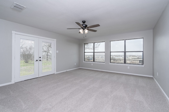 carpeted spare room with visible vents, a healthy amount of sunlight, french doors, and baseboards