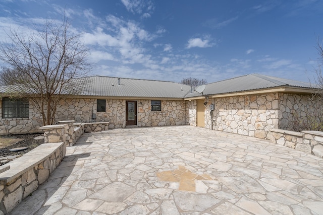 back of house with metal roof and a patio area