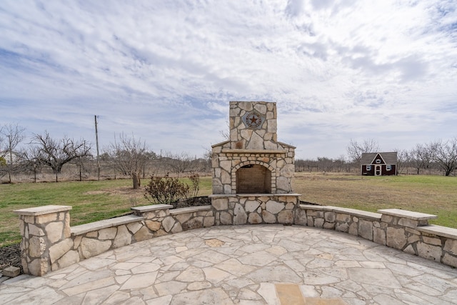 view of patio featuring a detached garage, an outbuilding, and an outdoor stone fireplace