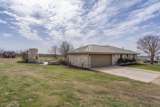 view of side of home featuring stone siding, an attached garage, concrete driveway, and a yard