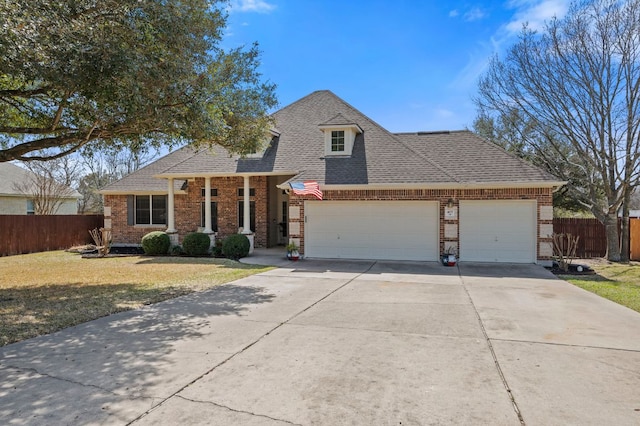 view of front facade with brick siding, a front lawn, fence, roof with shingles, and a garage