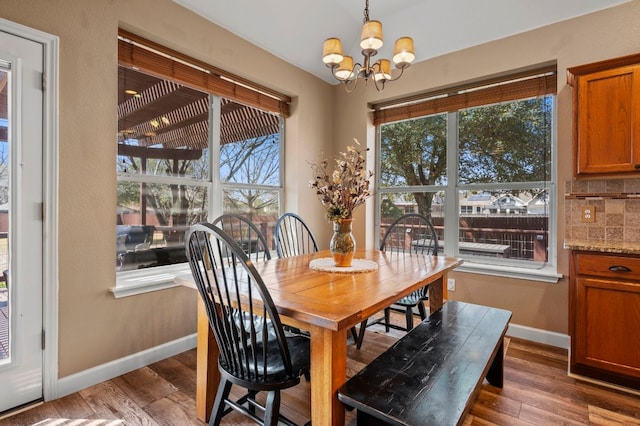 dining room with a chandelier, baseboards, and wood finished floors