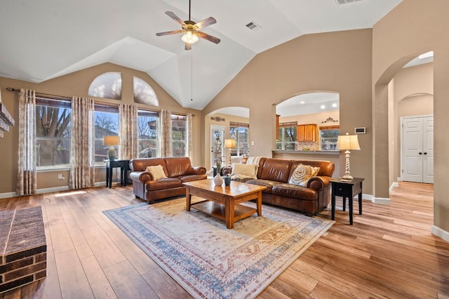 living area featuring arched walkways, visible vents, and light wood-type flooring