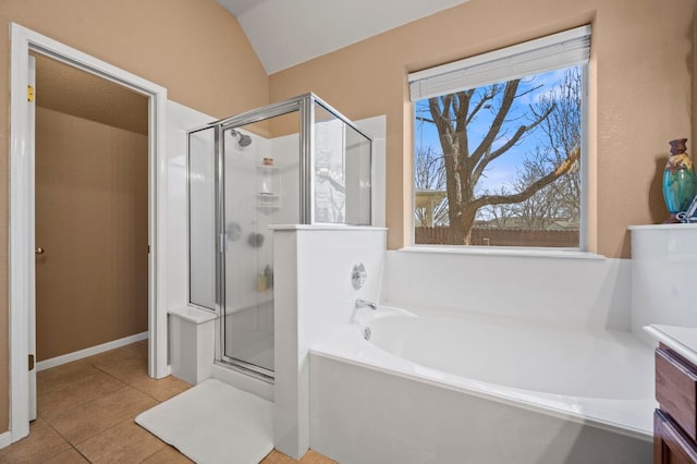 bathroom featuring tile patterned flooring, lofted ceiling, a garden tub, a stall shower, and vanity