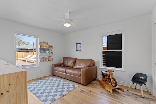 living room featuring ceiling fan, baseboards, and light wood-style flooring