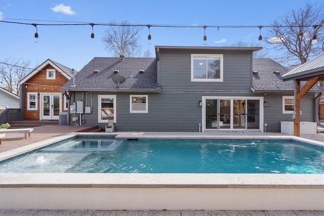 back of property with central AC unit, roof with shingles, a pool with connected hot tub, french doors, and a deck