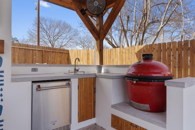 view of patio / terrace with a sink, exterior kitchen, and fence