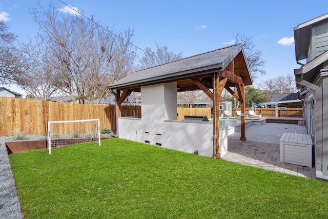 view of yard featuring a gazebo, an outdoor kitchen, a fenced backyard, and a patio area