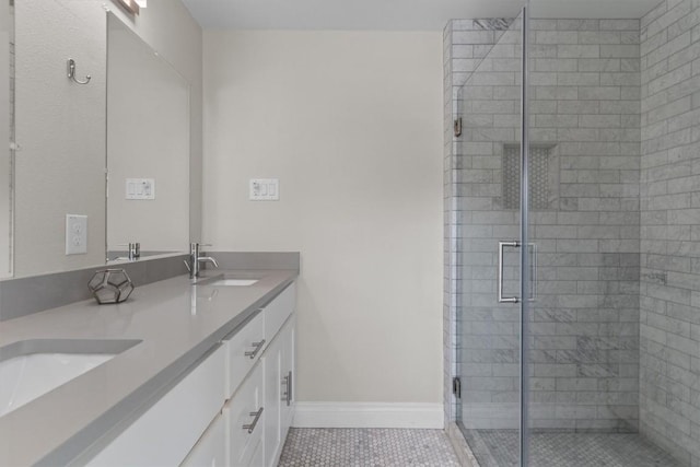 bathroom featuring double vanity, a stall shower, baseboards, and a sink