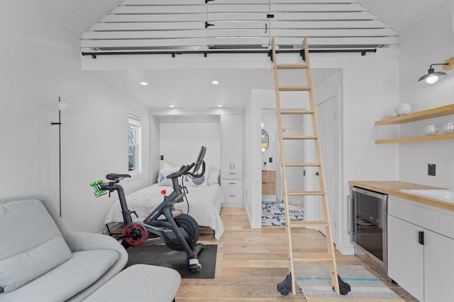 exercise area with lofted ceiling, wine cooler, recessed lighting, and light wood-style flooring