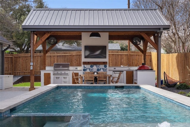 view of swimming pool with grilling area, an outdoor kitchen, and a fenced backyard