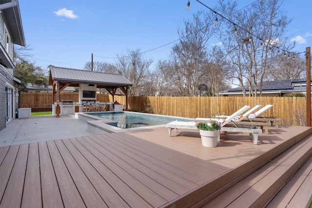 wooden deck with a fenced in pool, central air condition unit, exterior kitchen, a fenced backyard, and area for grilling