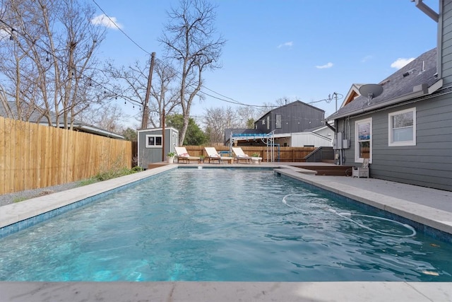 view of swimming pool featuring an outdoor structure, a fenced backyard, a fenced in pool, and a shed