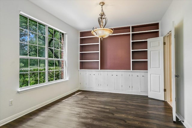 unfurnished dining area featuring dark wood-type flooring and baseboards