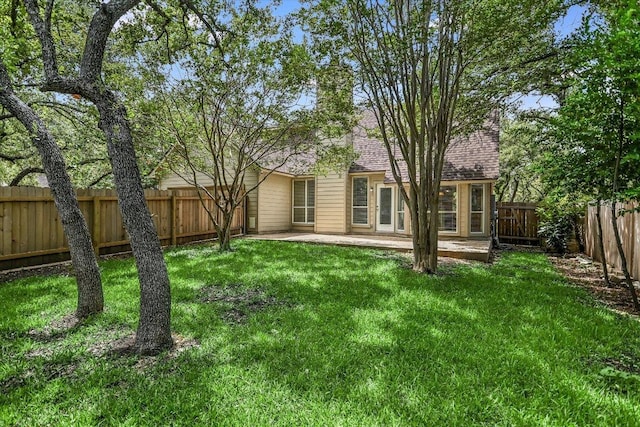 rear view of property with a patio area, a yard, a fenced backyard, and a shingled roof