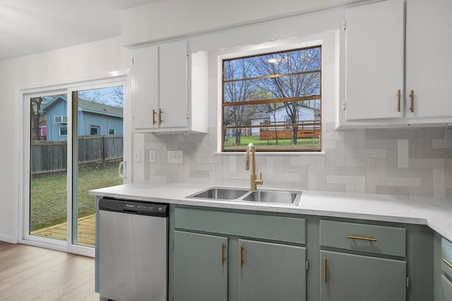 kitchen featuring a sink, tasteful backsplash, dishwasher, and light countertops