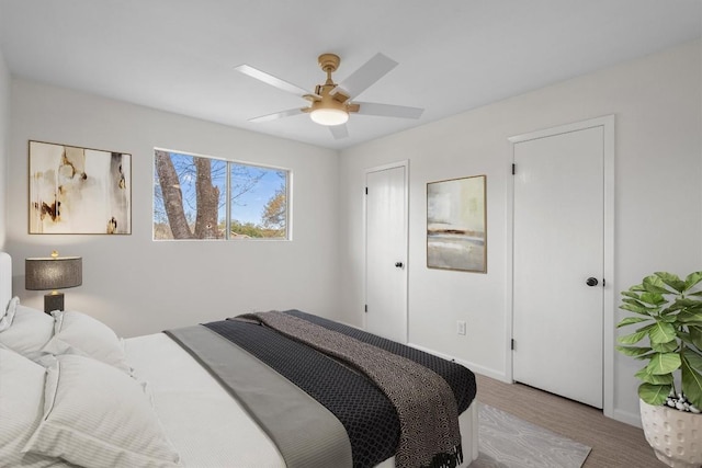 bedroom featuring ceiling fan, baseboards, and wood finished floors