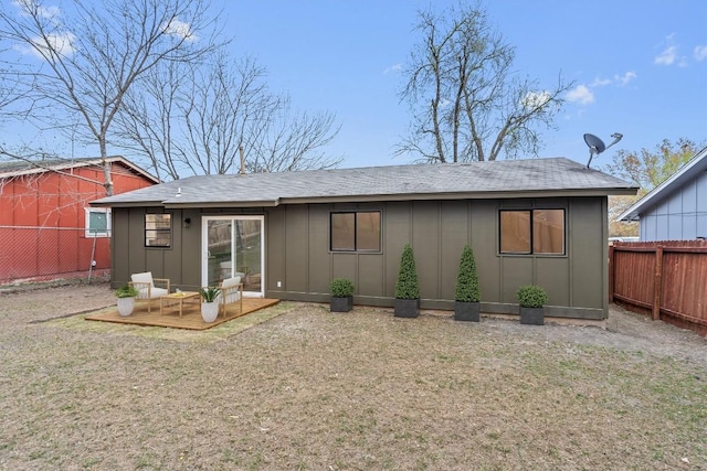 back of house featuring a yard, board and batten siding, a wooden deck, and a fenced backyard