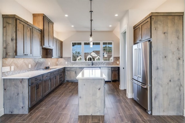 kitchen featuring a kitchen island, wood tiled floor, light countertops, decorative backsplash, and stainless steel appliances