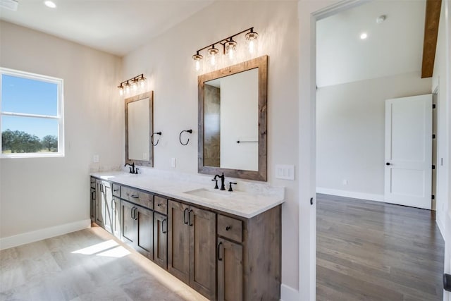 bathroom with double vanity, wood finished floors, baseboards, and a sink