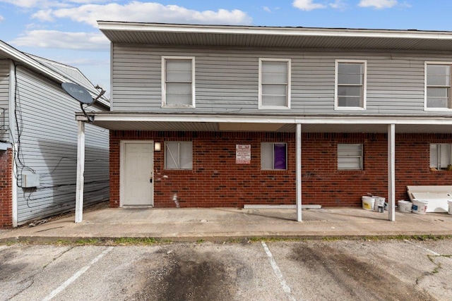 rear view of property with brick siding and uncovered parking