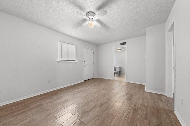 unfurnished room with wood finished floors, baseboards, visible vents, ceiling fan, and a textured ceiling