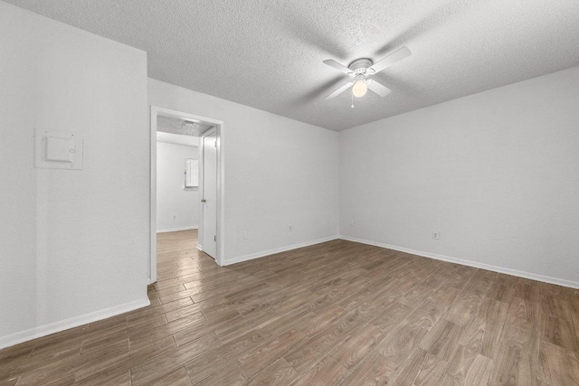 empty room with baseboards, a textured ceiling, a ceiling fan, and wood finished floors