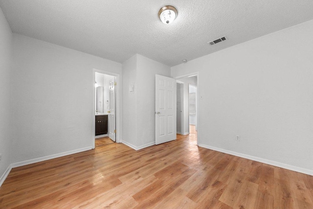 unfurnished bedroom featuring light wood-type flooring, visible vents, baseboards, and a textured ceiling