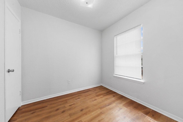 unfurnished room with baseboards, light wood-style floors, and a textured ceiling