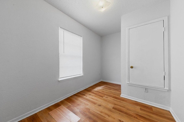 spare room with wood finished floors, baseboards, and a textured ceiling