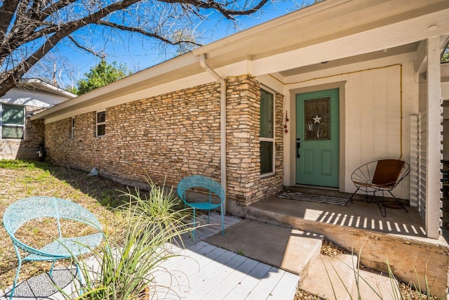 view of exterior entry with a patio and stone siding