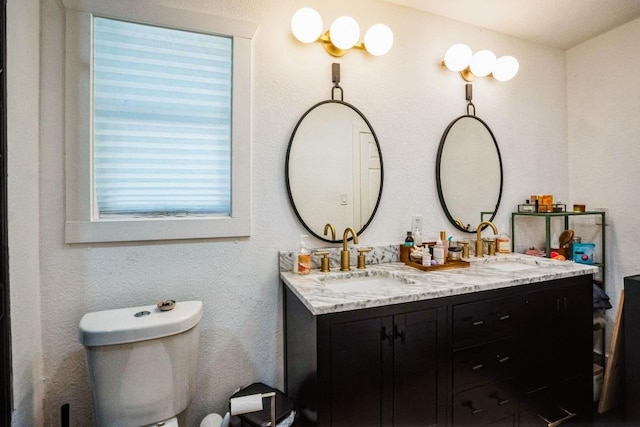 bathroom featuring double vanity, toilet, and a sink