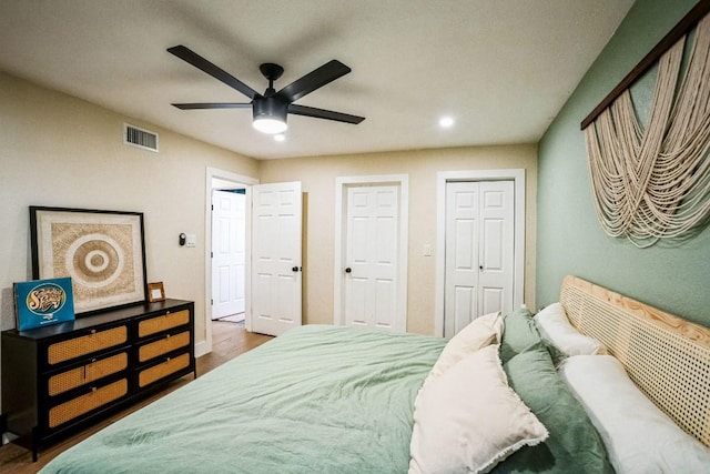 bedroom with ceiling fan, visible vents, baseboards, and wood finished floors