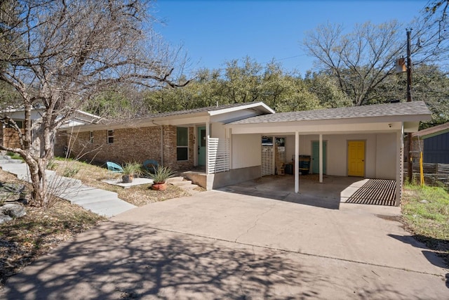 exterior space with an attached carport, brick siding, and driveway