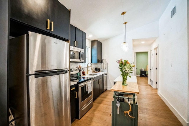 kitchen with visible vents, vaulted ceiling, appliances with stainless steel finishes, light wood-style floors, and a sink