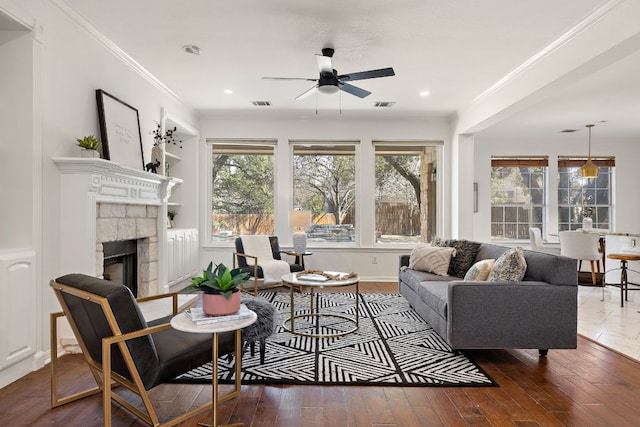 living area featuring visible vents, ornamental molding, a fireplace, and hardwood / wood-style floors