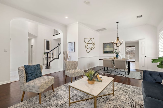 living room featuring arched walkways, visible vents, stairway, and wood finished floors