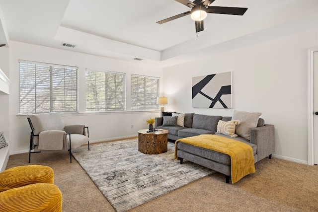 carpeted living area with visible vents, baseboards, and a tray ceiling