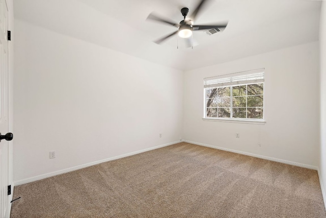 carpeted spare room featuring baseboards, visible vents, and ceiling fan