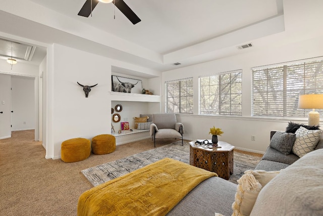 living room with visible vents, built in features, a tray ceiling, carpet, and attic access