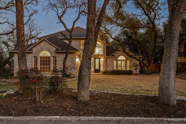 french provincial home with stone siding and a shingled roof