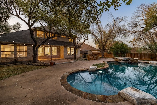 view of pool featuring a patio, a fenced backyard, outdoor dry bar, and a pool with connected hot tub