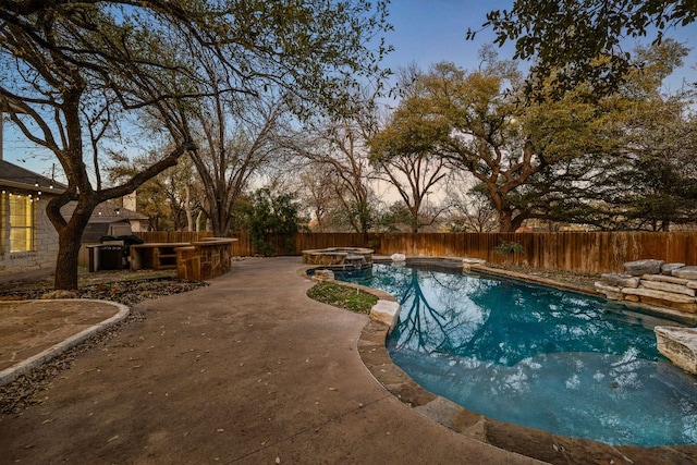 view of swimming pool with a patio, a pool with connected hot tub, and a fenced backyard