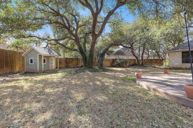 view of yard featuring an outdoor structure, a fenced backyard, and a patio area